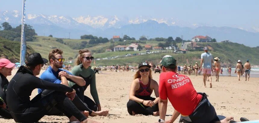 Surfkurs am Playa de Gerra mit den schneebedeckten Bergen im Hintergrund Surfkurs am Playa de Gerra mit den schneebedeckten Bergen im Hintergrund