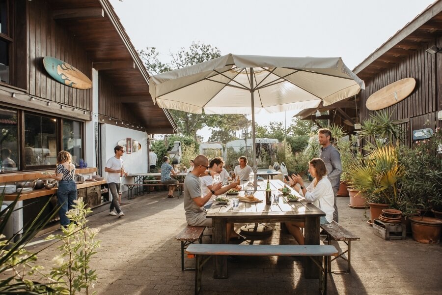 Frühstück und Surftheorie finden im sonnigen Innenhof der Atlantic Surf Lodge in Frankreich statt