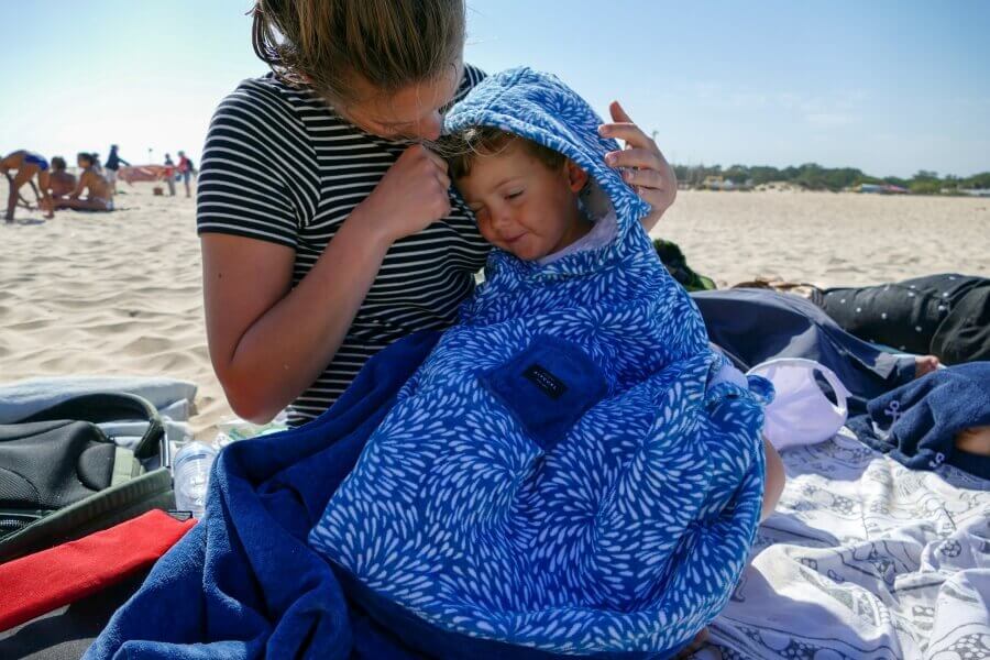 Mutter und Kind mit Surf Poncho am Strand