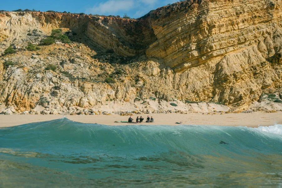 Wellen und Gruppe von Surfern am Surfspot Cabanas Velhas an der Algarve