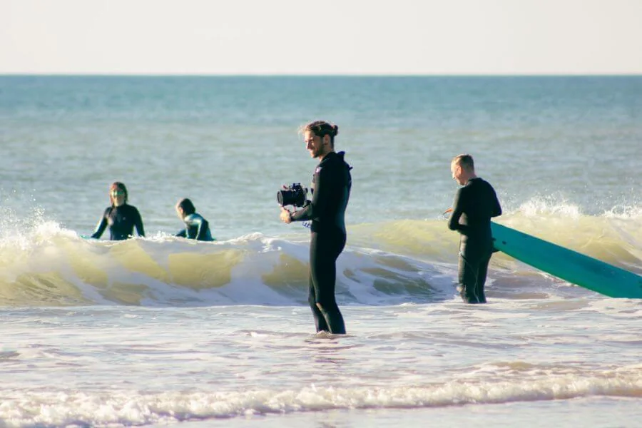 Der professionelle Surffotograf Sergio geht beim A-Frame Surfkurs in El Plamar mit Kamera ins Wasser