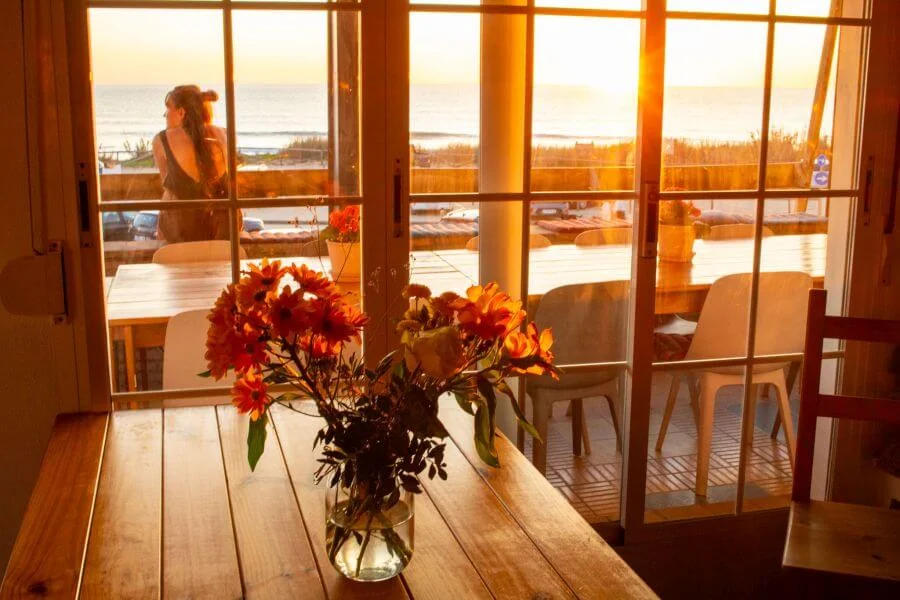 Gemeinschaftsraum mit Tischblumen und Meerblick im A-Frame Surfcamp El Palmar in Andalusien