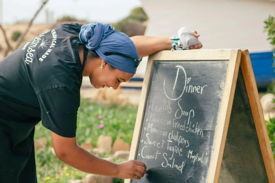 Köchin Sana schreibt das Dinner Menü an die Tafel vom Dreamsea Surfcamp in Imsouane Marokko
