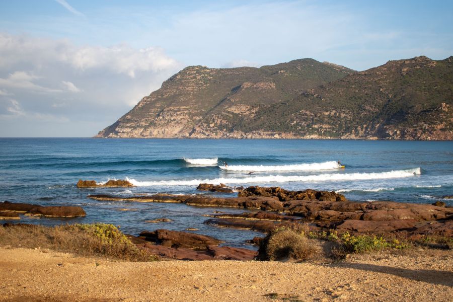 Wellen, Surfer und Berge auf Sardinien