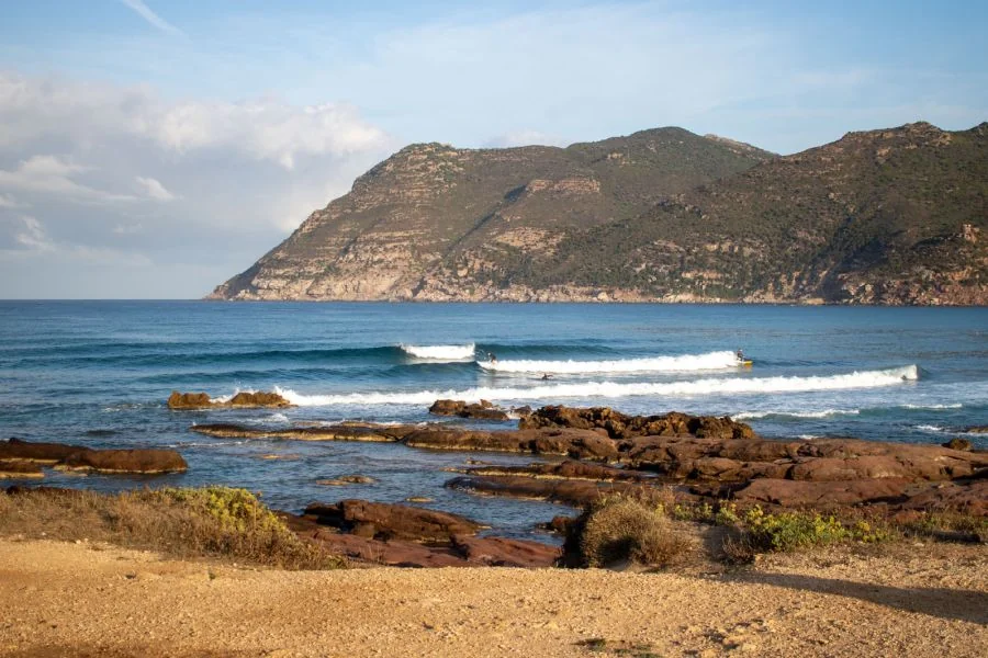 Wellen, Surfer und Berge auf Sardinien